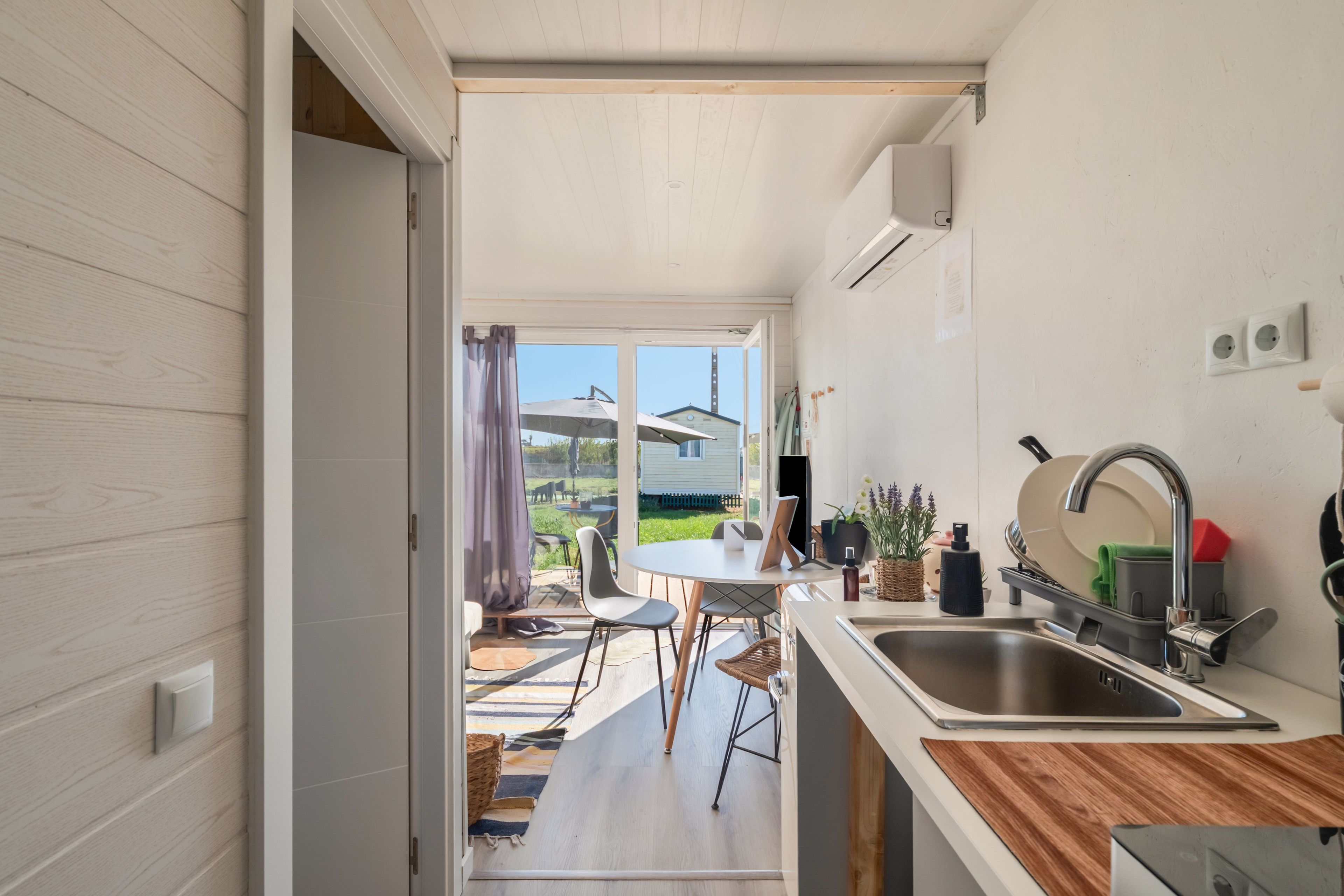 A modern kitchen with a dining area, a view of the outdoors, and a small garden.