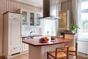 A kitchen with white cabinetry, a central island with seating, and a window providing natural light. - Holiday apartment with 2 bedrooms (Groß Zecher)