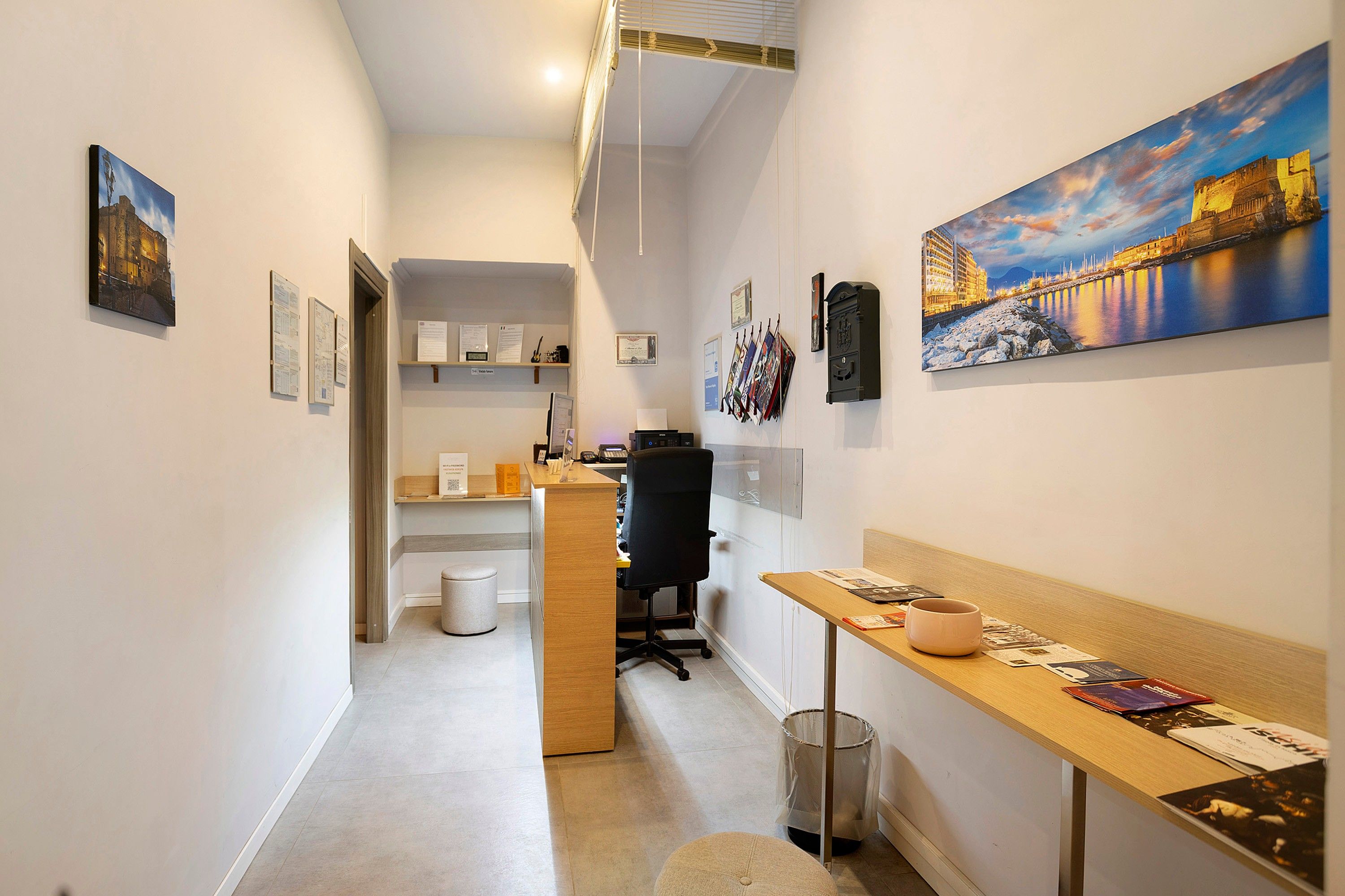 A hallway with a desk, chair, and a trash can.