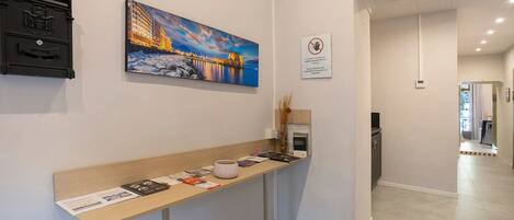 Un espace d’accueil avec un comptoir où sont exposées des brochures et un tableau représentant un paysage urbain.