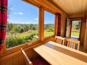 A wooden cabin with a large window overlooking a forested landscape. - Hvilebu - Charming and Traditional Cabin at Kikut, Geilo (Hol)