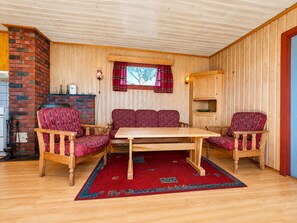 A cozy room with a wooden ceiling, a brick fireplace, a wooden table with four chairs, and a red rug. - Hvilebu - Charming and Traditional Cabin at Kikut, Geilo (Hol)
