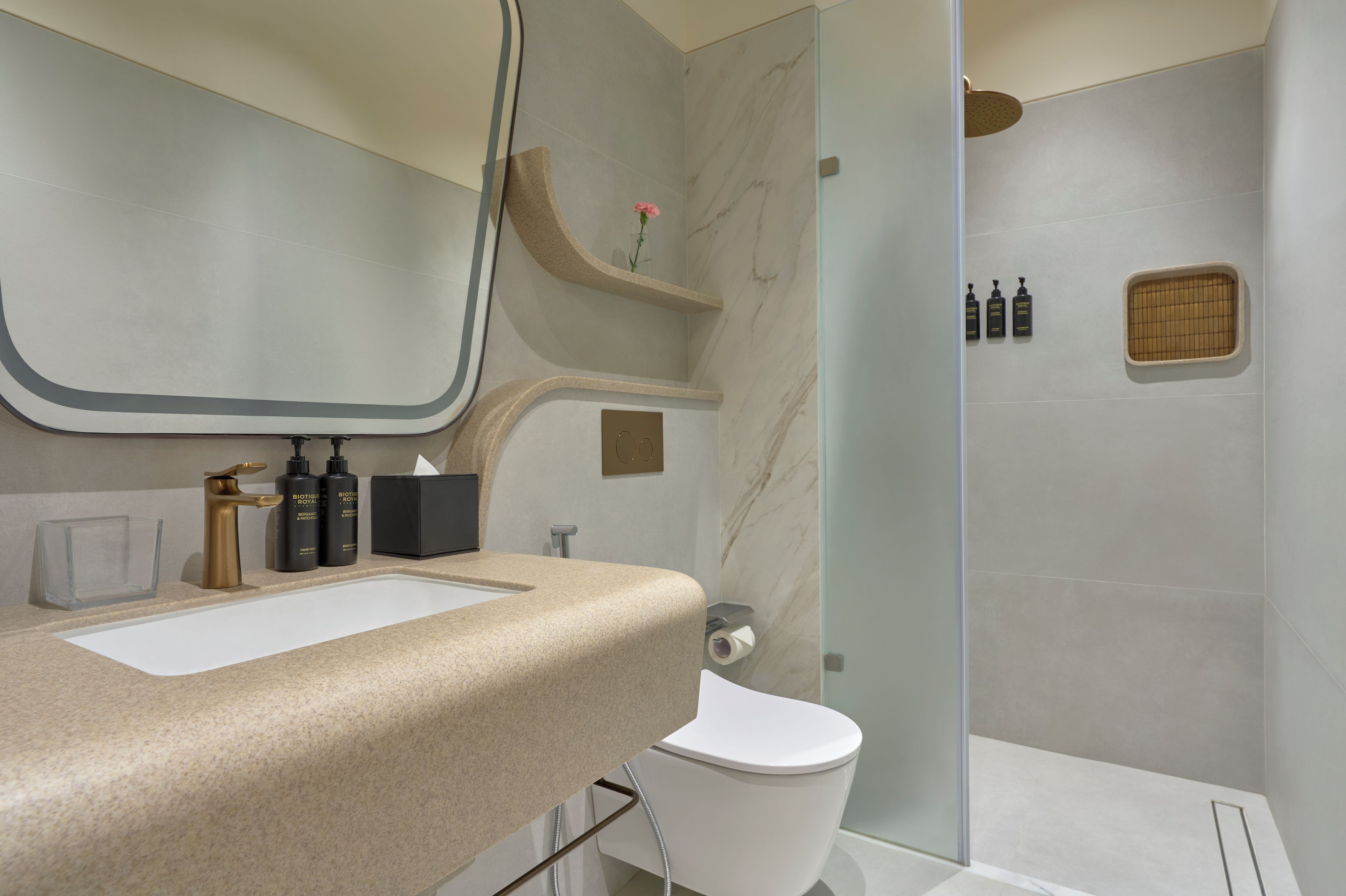 A bathroom with a white sink, a mirror, a toilet, and a shower area.