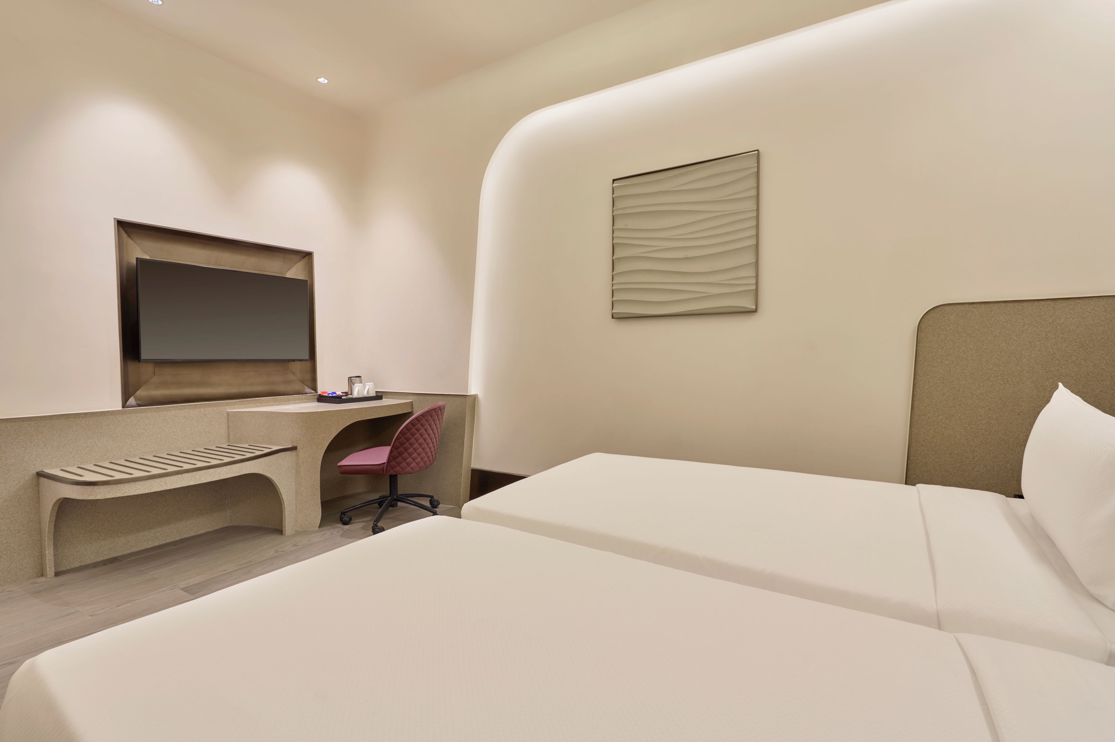 Ein Hotelzimmer mit einem Bett, einem Schreibtisch mit Stuhl, einem Fernseher und einem Wandbild.