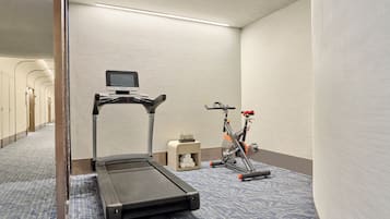 Habitación de hotel con una cinta de correr, bicicleta estática y una pequeña mesa con artículos de aseo.