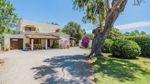 A two-story house with a gravel driveway, a patio with outdoor furniture, and a variety of potted plants. - Rustic Country Villa With Private Pool (Pollença)