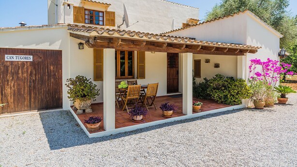 A two-story building with a covered patio, wooden furniture, and potted plants. - Rustic Country Villa With Private Pool (Pollença)