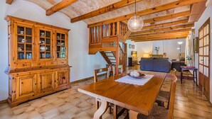 A dining area with a wooden table, chairs, a cabinet with glass doors, and a staircase leading to an upper level. - Rustic Country Villa With Private Pool (Pollença)