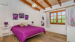 A bedroom with a bed, bedside tables, a desk, a window with curtains, and wall-mounted pictures. - Rustic Country Villa With Private Pool (Pollença)