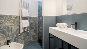 Ein modernes Badezimmer mit einem weißen Waschbecken, einem schwarzen Wasserhahn und einem Handtuchhalter.