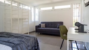Ein Schlafzimmer mit einem Bett, einem Sofa, einem Schreibtisch und einem Sessel.