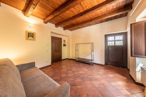 A room with a wooden ceiling, a sofa, a door, and a window.
