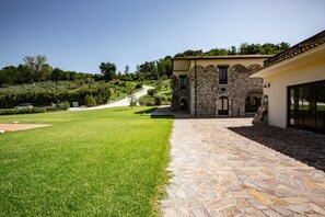 Ein Steinhaus mit gepflasterter Auffahrt und einem gepflegten Rasen.