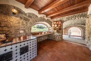 A rustic kitchen with stone walls, wooden beams, and a tiled backsplash.