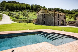 A stone building with a swimming pool in front.