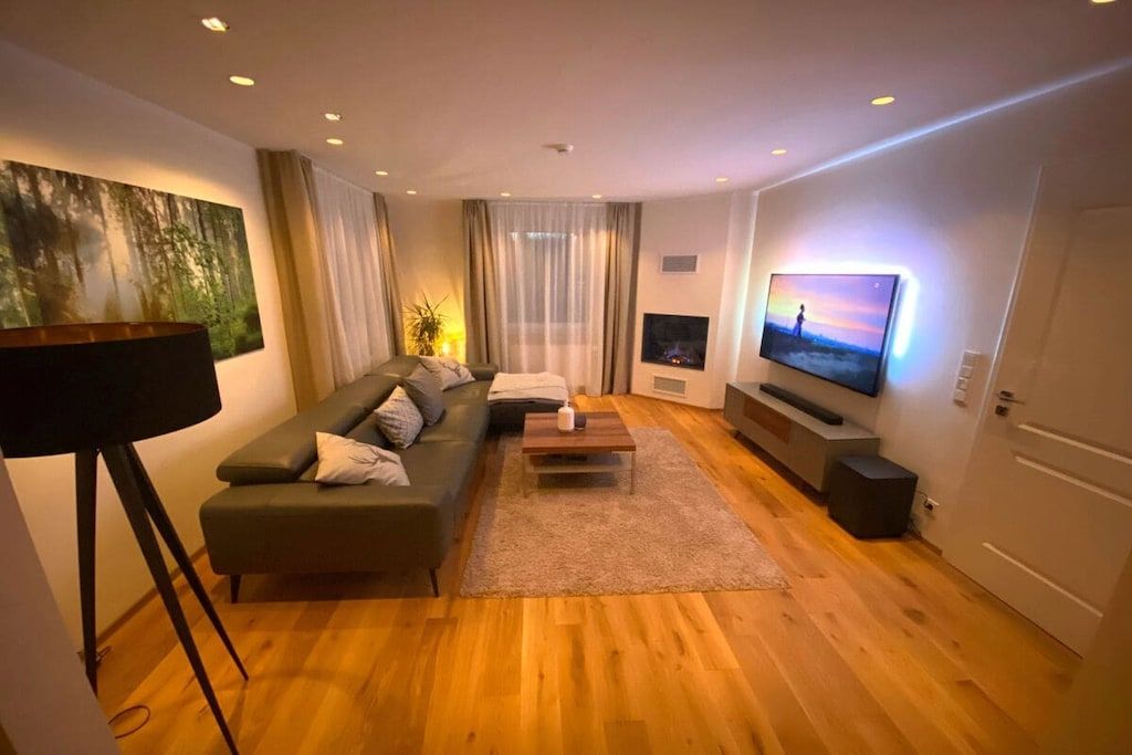 A modern living room with a sofa, coffee table, TV, and a painting on the wall.