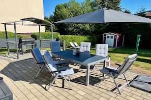 An outdoor patio with a table and chairs, a grill, and a covered seating area. - HarzVilla Bad Sachsa. (Bad Sachsa)