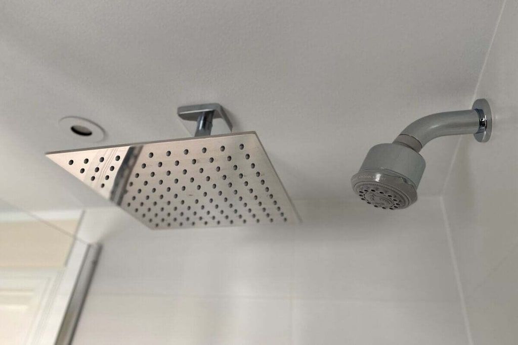 A showerhead with a square design and a curved pipe.