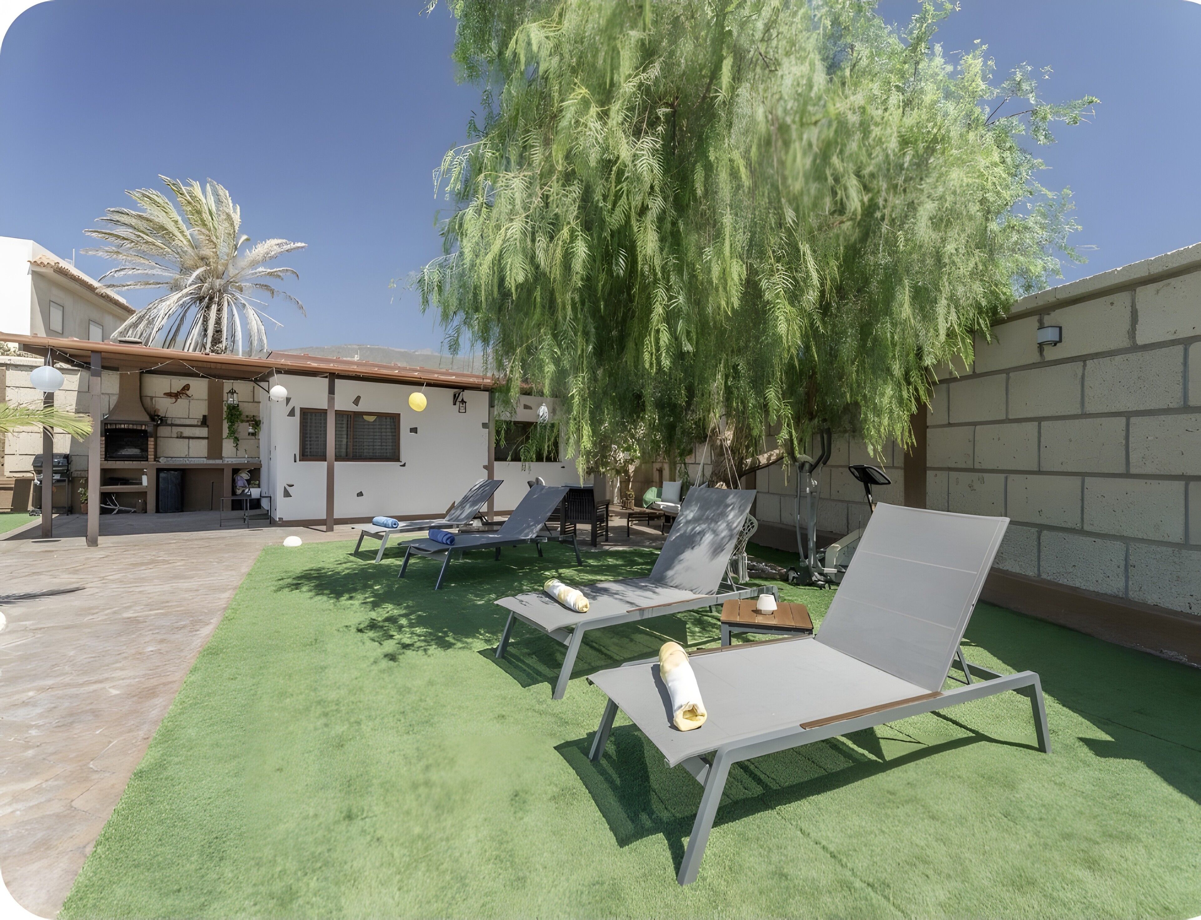 A patio area with outdoor seating, a pergola, and a wall-mounted grill.