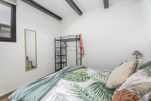 Ein Schlafzimmer mit einem Bett, einer Kleiderstange, einem Spiegel und einer Lampe.