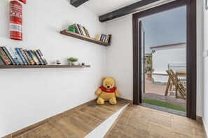 Ein Zimmer mit Holzboden, einem Teddybären und zwei Regalen mit Büchern und einer kleinen Pflanze.