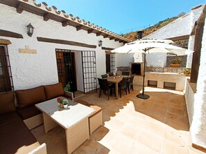 Eine Terrasse im Freien mit Esstisch und Stühlen, einer Sitzecke und einem Grillbereich.