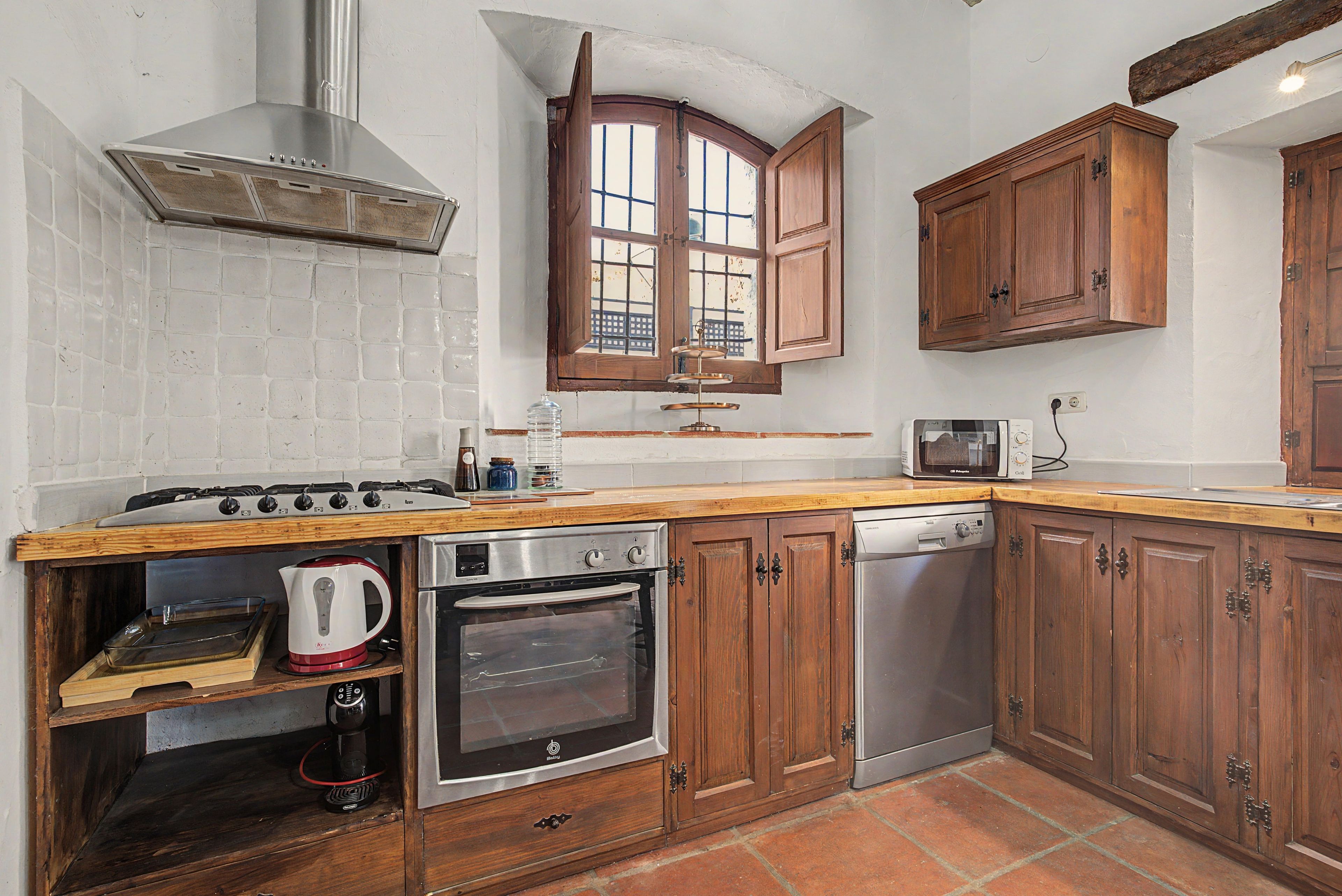 Una cocina con armarios de madera, estufa a gas, horno y lavavajillas.