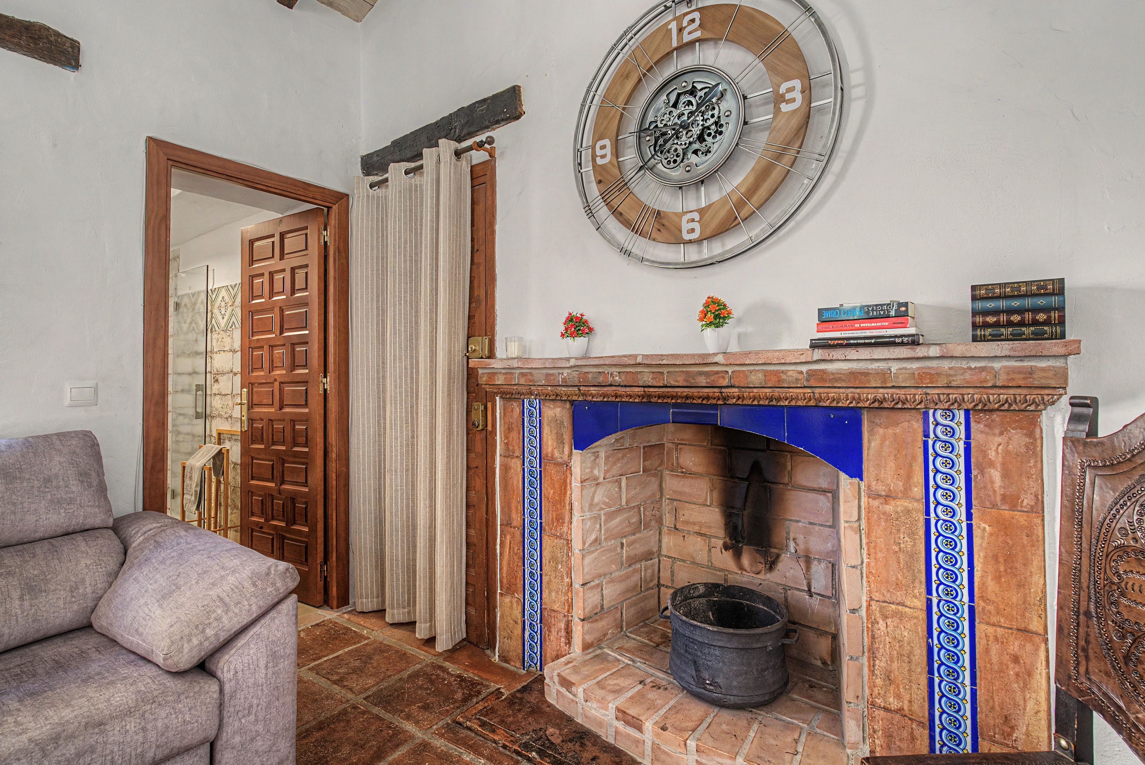 Una habitación con chimenea, puerta de madera, un reloj y una estantería.