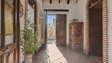 Un pasillo con suelo de baldosas, puertas de madera y una planta en maceta.