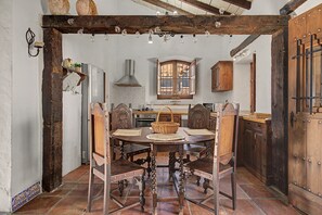 A rustic dining area with a wooden table, chairs, and a large window.