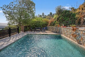 A swimming pool with a stone wall and a wooden deck.