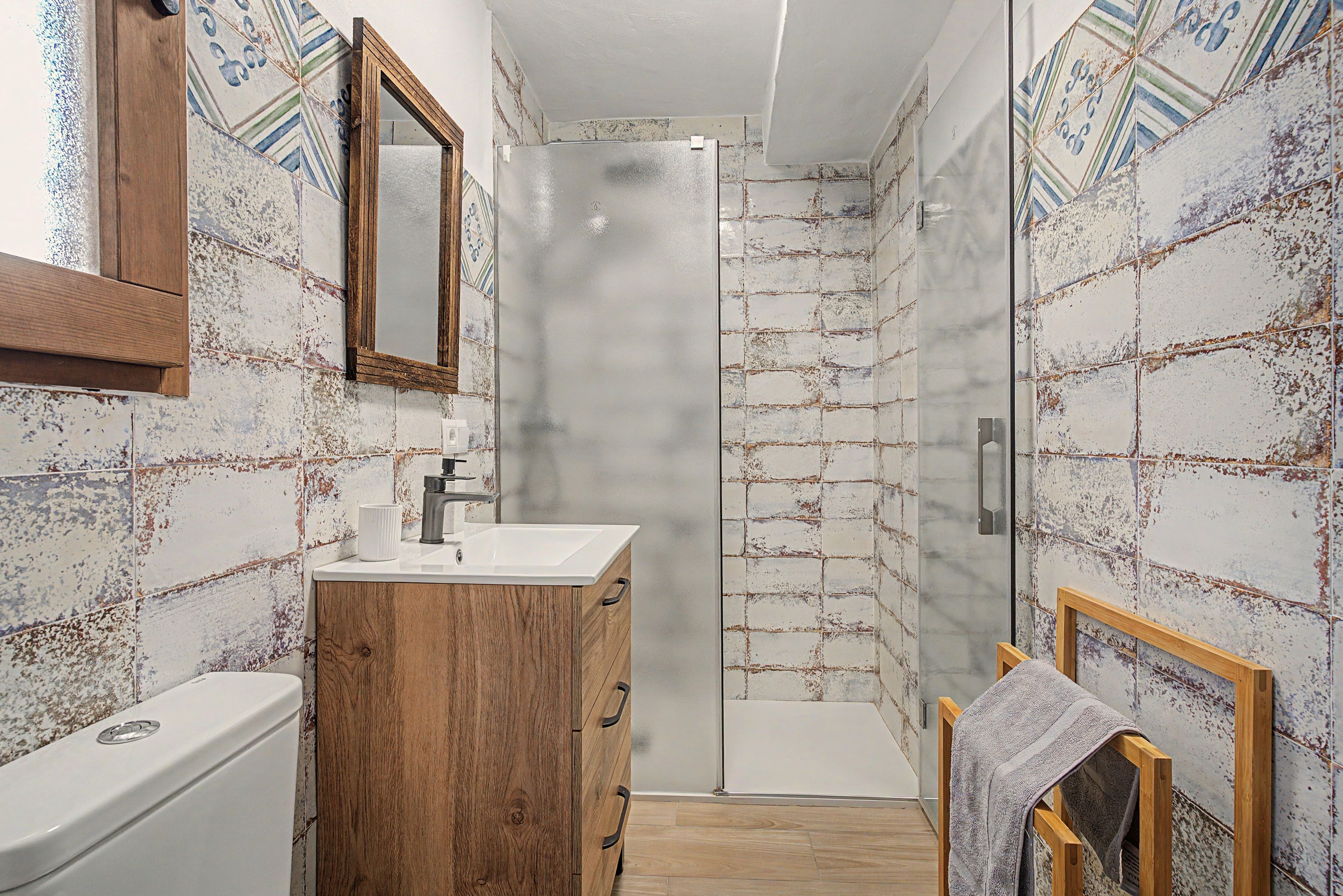 Une salle de bain avec un meuble en bois, un lavabo et un espace douche.