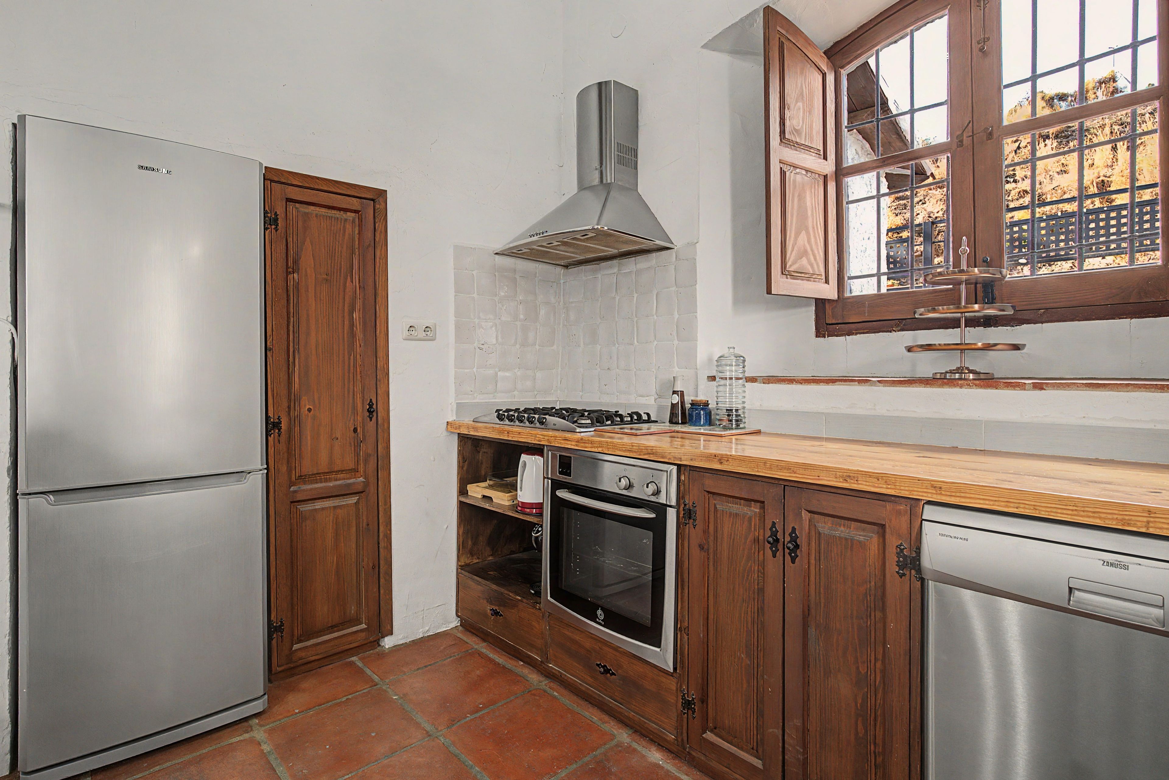 Cocina compacta equipada con refrigerador, estufa, horno y lavavajillas.