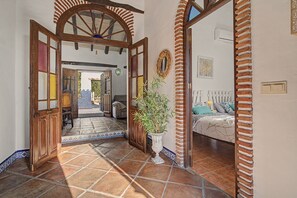 A hallway with a tiled floor leading to a bedroom with a bed and a nightstand. - Cortijo Eucalipto 1 with Sea Views, Private Pool, and Air Conditioning (Nerja)