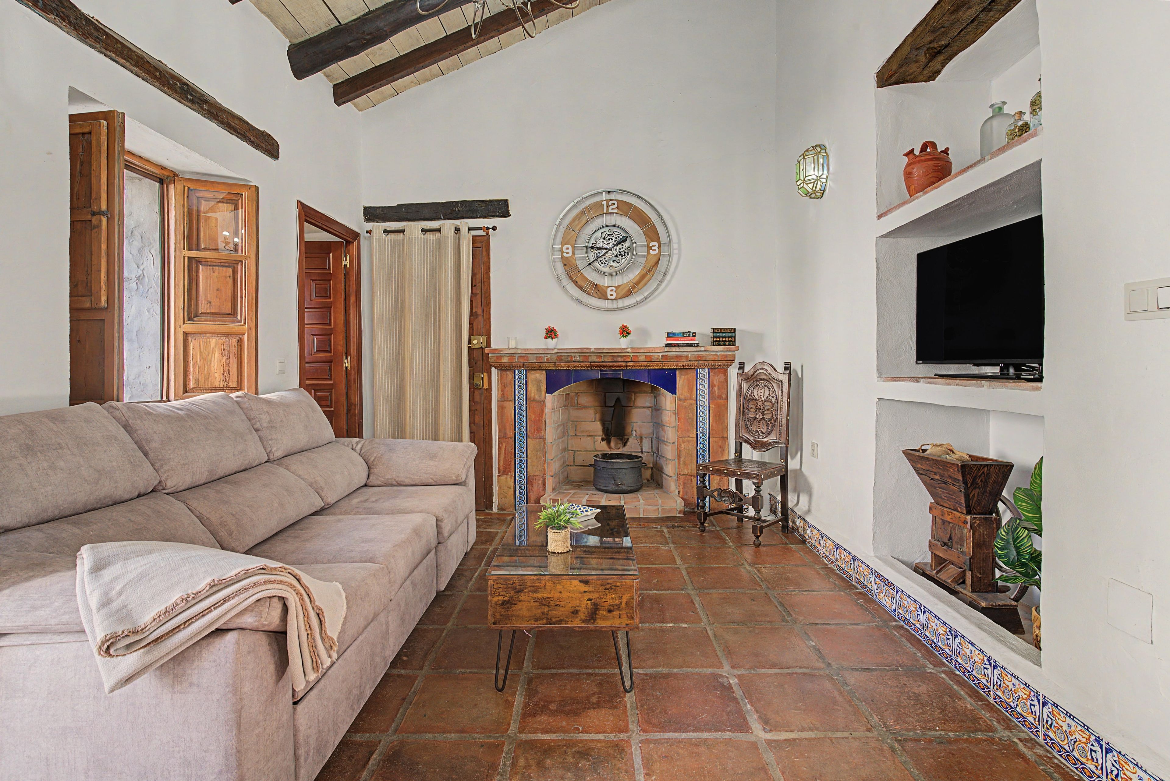 Una sala de estar con un sofá, una chimenea, un reloj y un televisor.