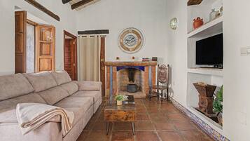 Una sala de estar con un sofá, una chimenea, un reloj y un televisor.