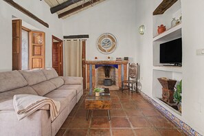 A living room with a sofa, a fireplace, a clock, and a television.