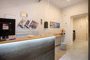 A reception area with a counter, a digital screen, and a sign indicating check-out times. - Double Room with External Bathroom, Wi-Fi and Air Conditioning (Napoli)