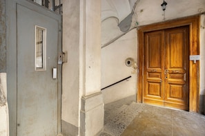 A hallway with a grey door on the left and a wooden door on the right. - Double Room with External Bathroom, Wi-Fi and Air Conditioning (Napoli)