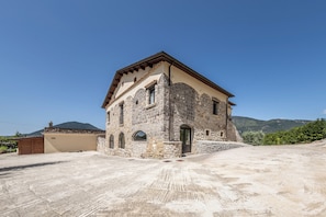 A stone building with a sloped roof, a small porch, and a clear sky in the background.