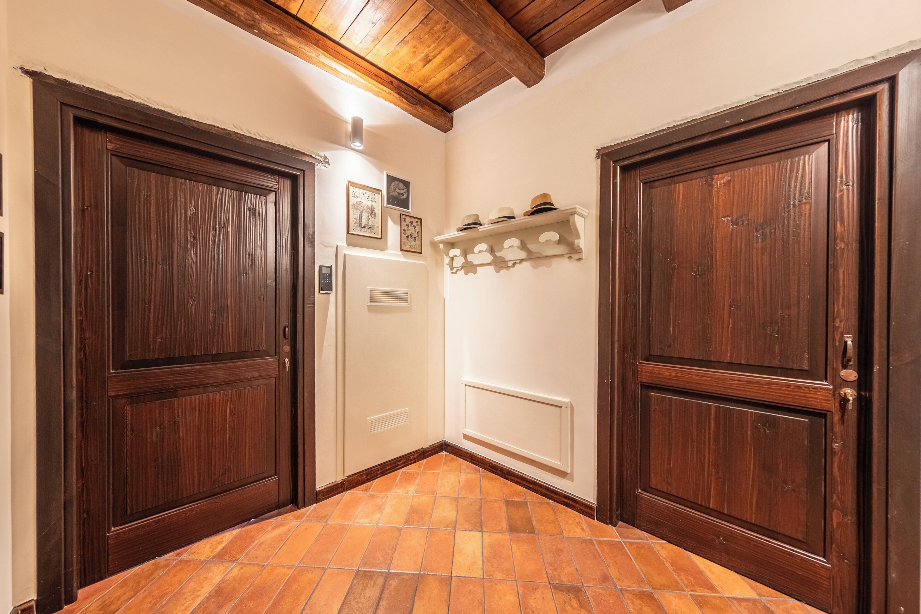 A hallway with wooden doors, a white radiator, and a shelf with hats.