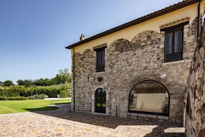 A stone building with a tiled entrance and a large arched window. - Dimora Santē – Historic Villa Surrounded by Olive Trees (Campania)