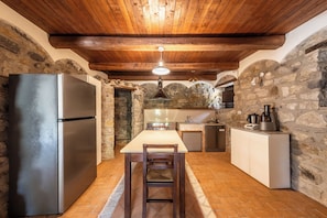 Una cocina rústica con pared de piedra, techo de madera y una isla central con asientos.