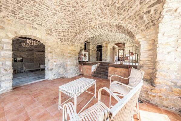 Un interior de paredes de piedra con zona de comedor amueblada con mobiliario de metal blanco.