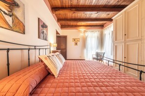 A bedroom with a bed, a nightstand, a chair, and a wooden ceiling.
