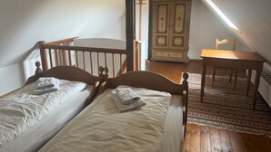 A bedroom with two single beds, a wooden dresser, a table, and a chair. - Cozy Holiday Apartment with Garden in Solzow Farmhouse (Südmüritz)