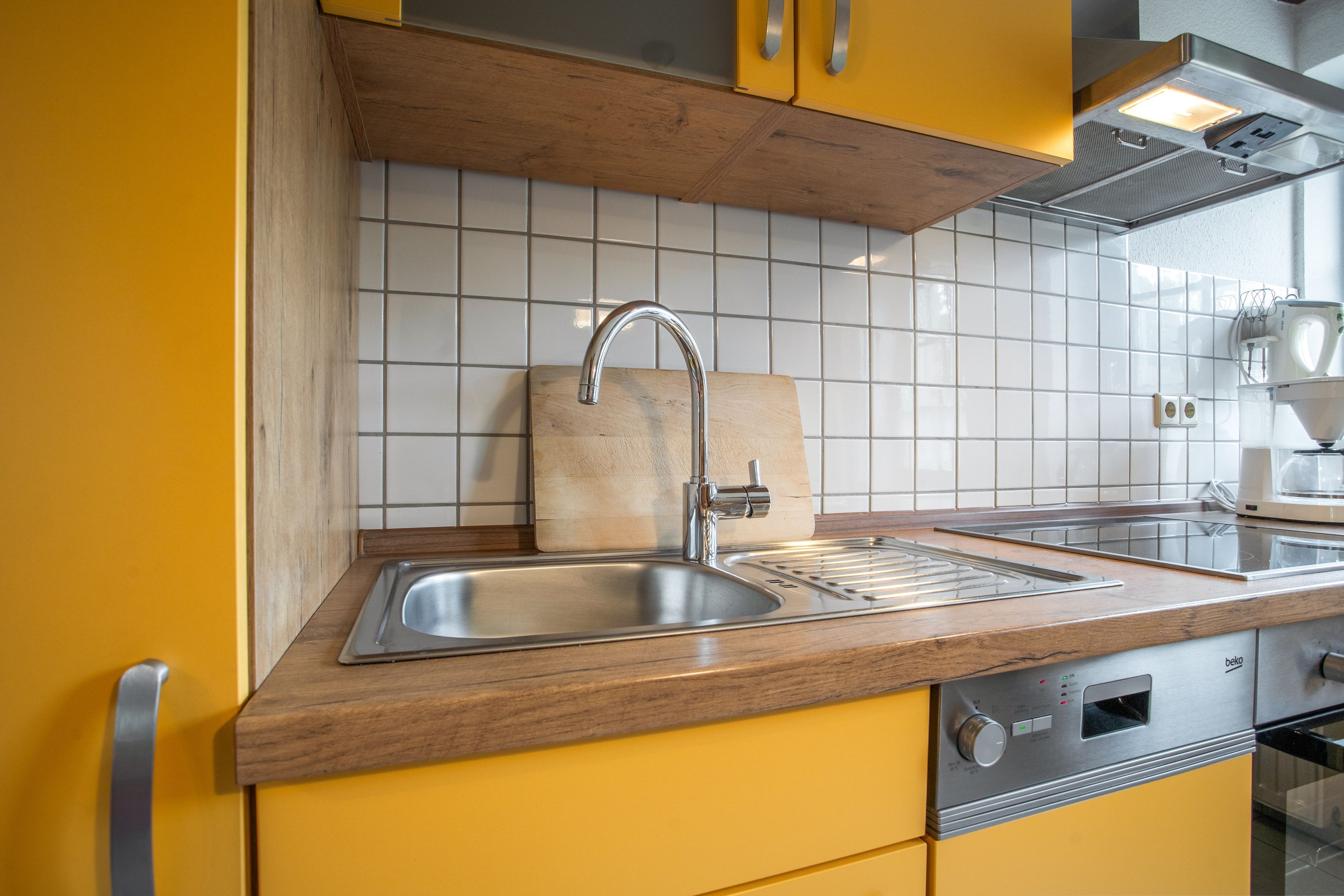Eine Küche mit Spüle aus Edelstahl, einer Holz Arbeitsplatte und einem eingebauten Backofen.