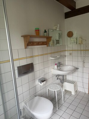 Une salle de bain comprenant des toilettes, un lavabo et un espace douche.