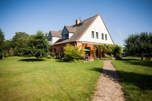 Une maison à deux étages, dotée d’un toit en pente, d’une cheminée bien visible et d’un chemin pavé menant à l’entrée.