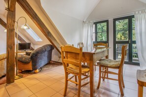 Una habitación acogedora con techo inclinado, mobiliario de madera y ventanas amplias.